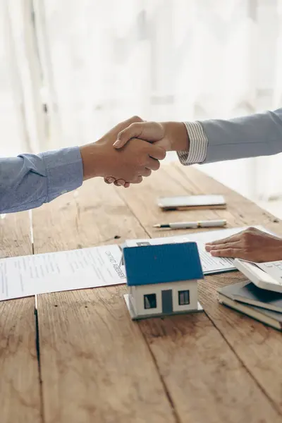 A bank loan officer shakes hands with a customer to congratulate him after approving a home loan. A bank loan officer shakes hands with a customer to congratulate him after signing a loan contract.