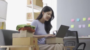 İnternette kıyafet satan Asyalı bir kız dairede dizüstü bilgisayar kullanıyor, internet günlüğü için blog kaydediyor, evdeki internet giyim mağazasında canlı yayında sevimli bir kadın var.