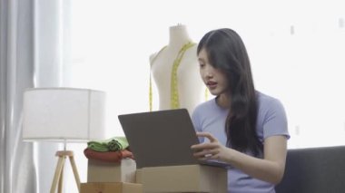 İnternette kıyafet satan Asyalı bir kız dairede dizüstü bilgisayar kullanıyor, internet günlüğü için blog kaydediyor, evdeki internet giyim mağazasında canlı yayında sevimli bir kadın var.
