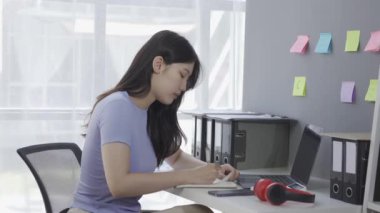 Kulaklık takan genç Asyalı kız öğrenci online ders alırken ya da konferans verirken internette geziniyor ve Google Zoom videosu çekiyor.