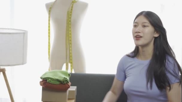 アパートでラップトップを使用してオンラインで服を販売するアジアの少女 ファッションブロガーは オンラインブログのビデオを記録します 自宅でインターネットの衣料品店でライブ放送中のかわいい女性 — ストック動画