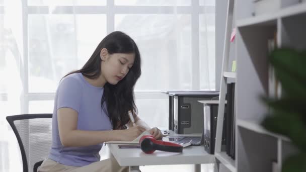 年轻的亚洲女学生带着耳机 一边参加在线课程或讲座 一边用笔记本电脑上网 一边用Google Zoom视频通话 — 图库视频影像