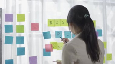 Genç girişimci, Asyalı muhasebeci cam üzerine not tutuyor yaratıcı Asyalı kişi kavramı, iş yerinde genç girişimci