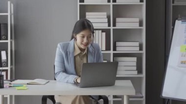 Asyalı genç bir kadın evdeki oturma odasındaki masada dizüstü bilgisayarla çalışıyor Asyalı iş kadınının başarısını kutlamak için.