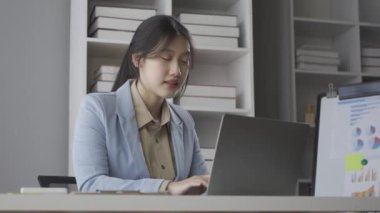 Asyalı genç bir kadın evdeki oturma odasındaki masada dizüstü bilgisayarla çalışıyor Asyalı iş kadınının başarısını kutlamak için.