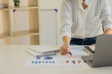 Çalışma masasında çalışan işadamı, hesap makinesiyle hesap makinesini kullanarak ofis mali muhasebe konseptinde hesap, iş raporu ve dizüstü bilgisayarla rakamları hesaplıyor. Resmi kapat.