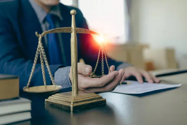 Law and Justice Lawyer working with documents and laptop, hammer, scale at wooden table in office Close-up of judge in suit or lawyer Legal advice and services