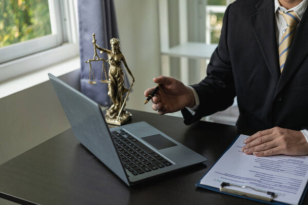 Law and Justice Lawyer working with documents and laptop, hammer, scale at wooden table in office Close-up of judge in suit or lawyer Legal advice and services