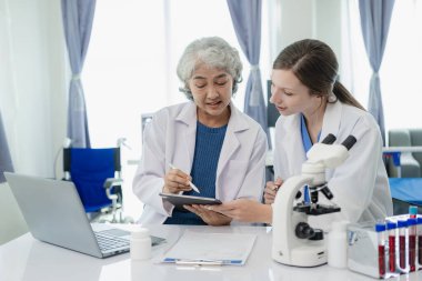 Laboratuvar, yaşlı kadın doktor ve kadın tüpte kanla tıbbi araştırma yapıyorlar. Beyaz önlüklü güzel bir kadın ofisinde oturmuş laboratuarda kan örneğiyle çalışıyor.