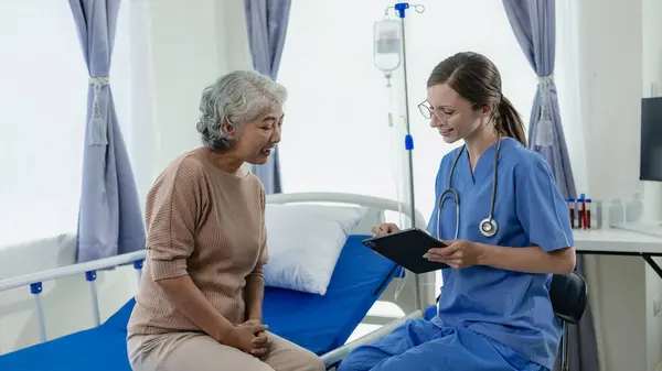 クリップボードを持つ女性医師は 病院のシニア女性またはデジタルタブレットの医師で高齢女性患者と話すか 女性患者と医療専門家を治療するための治療計画 — ストック写真