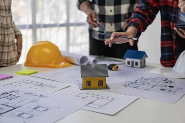 Mühendis ve işadamı ofiste inşaat projesini tartışıyorlar. Mühendislerden oluşan bir ekip yeni projenin planlarını gözden geçiriyorlar.