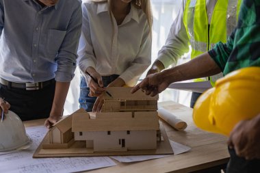 Mühendis ve işadamı ofiste inşaat projesini tartışıyorlar. Mühendislerden oluşan bir ekip yeni projenin planlarını gözden geçiriyorlar.