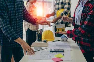 Mühendis ve işadamı ofiste inşaat projesini tartışıyorlar. Mühendislerden oluşan bir ekip yeni projenin planlarını gözden geçiriyorlar.