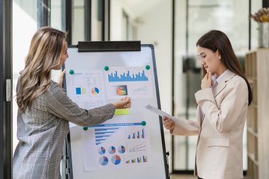 Profesyonel ve odaklanmış Asyalı işkadını veya denetçi müşterilerle yeni bir başlangıç projesinin sunumunu tartışarak planlarını tartışıyor. Ofisteki istatistik ve yatırım pazarlarını analiz et.