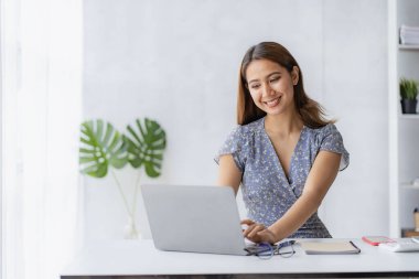 Keyifli, mutlu ve bağımsız iş yapan genç bir kadın. Ev bilgisayarını kullanan çekici bir kadın. İnternette laptop yazılımı kullanarak çalışıyor.