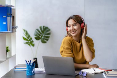 Keyifli, mutlu ve bağımsız iş yapan genç bir kadın. Ev bilgisayarını kullanan çekici bir kadın. İnternette laptop yazılımı kullanarak çalışıyor.