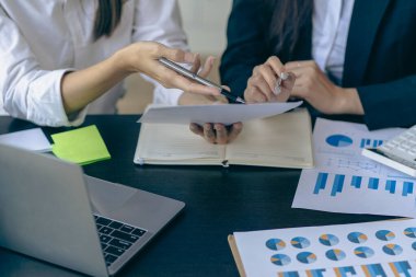 İş adamları mali raporları analiz ediyor ve hesap makinesi kullanıyorlar. Muhasebe hesaplamaları ve ortaklar şirketin satış planlarını analiz etmek için mali raporlara işaret ediyor..