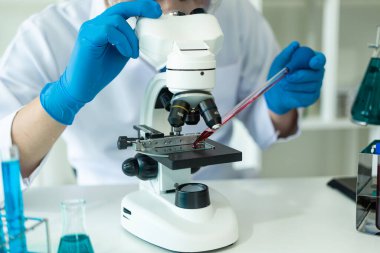 Kimya laboratuvarında kimya laboratuvarında DNA molekülü inceleyen bir doktor. Kimya laboratuarında mikroskop kullanarak sıvı örneği inceleyen bir bilim adamı.