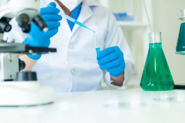 Kimya laboratuvarında kimya laboratuvarında DNA molekülü inceleyen bir doktor. Kimya laboratuarında mikroskop kullanarak sıvı örneği inceleyen bir bilim adamı.