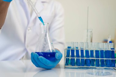 Kimya laboratuvarında kimya laboratuvarında DNA molekülü inceleyen bir doktor. Kimya laboratuarında mikroskop kullanarak sıvı örneği inceleyen bir bilim adamı.