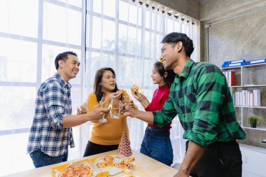 Arkadaşlarıyla birlikte mutlu Asyalı gençler parti, yemek, pizza, çatal bıçak takımlı atıştırmalıklar ve lezzetli yiyecekler eşliğinde kadeh tokuşturmayı kutluyor.