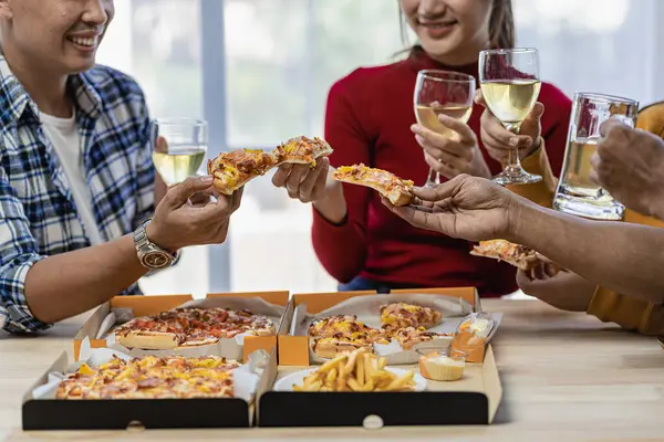 Arkadaşlarıyla birlikte mutlu Asyalı gençler parti, yemek, pizza, çatal bıçak takımlı atıştırmalıklar ve lezzetli yiyecekler eşliğinde kadeh tokuşturmayı kutluyor.