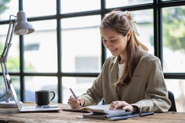 Asyalı öğrenci, genç bayan Millennial kadın teste hazırlanıyor ya da bir kafede dizüstü bilgisayarla internette sörf yapıyor, çevrimiçi bir not defterine, webinar 'a, yabancı dilleri öğreniyor.