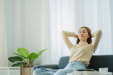 Önünde dizüstü bilgisayarla oturan mutlu, rahat, rahat bir kadın. Kolları başının üstünde, yaşam tarzı, refah ve sağlık kavramı..