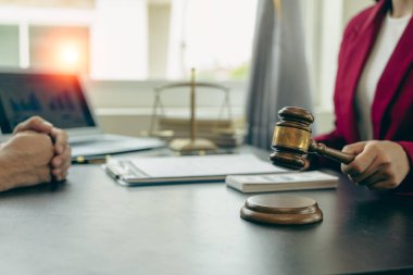 Yargıç, müvekkillerine yardım etmek için avukatlık bürosundaki avukatla iş sözleşmesi belgelerini tartışıyor ya da tavsiyelerde bulunuyor..