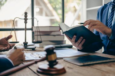 Yargıç, müvekkillerine yardım etmek için avukatlık bürosundaki avukatla iş sözleşmesi belgelerini tartışıyor ya da tavsiyelerde bulunuyor..