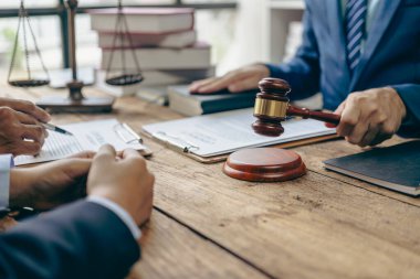 Yargıç, müvekkillerine yardım etmek için avukatlık bürosundaki avukatla iş sözleşmesi belgelerini tartışıyor ya da tavsiyelerde bulunuyor..