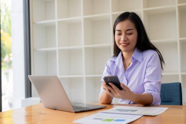 Evden çalışan hırslı Asyalı kız dizüstü bilgisayar ekranlarına ve mali belgelere bakıyor, kadın uzaktan çalışırken e-postaları kontrol ediyor veya araştırma yapıyor.