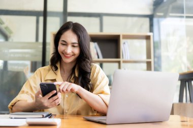 Evden çalışan hırslı Asyalı kız dizüstü bilgisayar ekranlarına ve mali belgelere bakıyor, kadın uzaktan çalışırken e-postaları kontrol ediyor veya araştırma yapıyor.