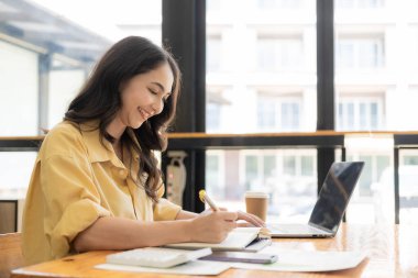 Evden çalışan hırslı Asyalı kız dizüstü bilgisayar ekranlarına ve mali belgelere bakıyor, kadın uzaktan çalışırken e-postaları kontrol ediyor veya araştırma yapıyor.