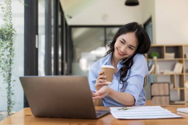 Evden çalışan hırslı Asyalı kız dizüstü bilgisayar ekranlarına ve mali belgelere bakıyor, kadın uzaktan çalışırken e-postaları kontrol ediyor veya araştırma yapıyor.