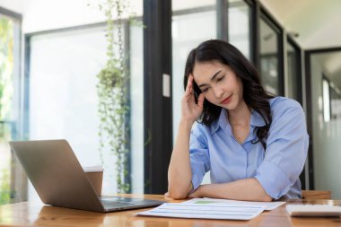 Yorgun Asyalı iş adamının evrak işlerinden başı ağrıyor ve ofiste bilgisayar ekranına bakıp, iş yerinde midesi bulanıyor.