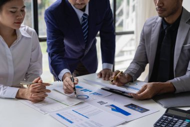 Müşterilerle konuşan ve ofis masasındaki müşterilere yatırım raporlarını gösteren, veri, bütçe çizelgeleri veya yasal sonuçları gösteren mutlu genç bayan finans danışmanı..