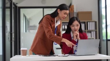 İki genç Asyalı iş kadını ofiste mali belgeler üzerinde çalışarak finansal istatistikleri dizüstü bilgisayarlarla analiz ediyorlar. Şirketin bütçesini ve muhasebesini planla.