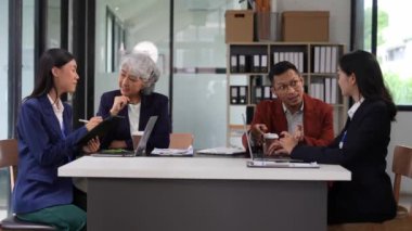 Asya iş dünyası finans ekibi proje beyin fırtınasında birlikte çalışıyor. İş birliği yapıyor ve stratejik planlama şirketi olarak çalışıyor. Finans belgeleri ve dizüstü bilgisayarı masada.