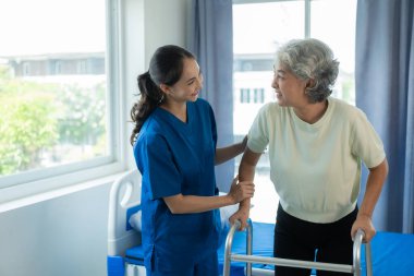 Huzurevindeki genç bir Asyalı hemşire yaşlı bir kadınla ilgileniyor. Uzman hekim, yaşlı hastaların sağlıkları için egzersiz yapmaları için fizik tedavi hizmetleri sunar..