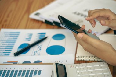 İş adamı, grafik ve grafik veri analizi için iş belgesine işaret ediyor ve elinde kalem tutan ve kar kavramını analiz etmek için mali belgeleri işaret eden muhasebe işkadını