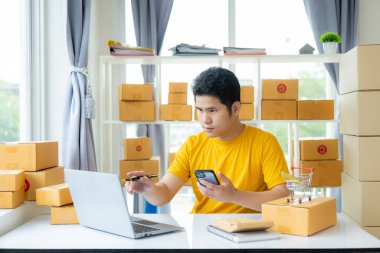 Küçük işletme, KOBİ iş konsepti müşterilere çevrimiçi isim sırasına göre çeşitli paket kutuları düzenleyen genç Asyalı adam.