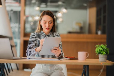 Profesyonel iş kadını, kurumsal pazarlama müdürü, elinde dijital tablet bulunan kadın işçi, tablette yeni bir girişimin bilgilerini okuyor ve iş stratejisi ve planlarını inceliyor..