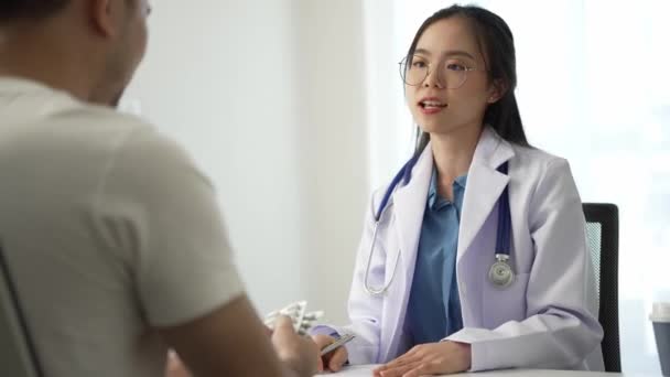 病院オフィスのテーブルに座っている健康診療所の医師の相談中に男性患者を持つアジアの女性医師 — ストック動画