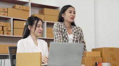 İki genç Asyalı kadın, KOBİ müşterisinden yeni bir sipariş aldıktan sonra mutlu ve heyecanlılar. Ticari denetim çevrimiçi pazarlama KOBİ girişimci ambalaj kutusu 4k video