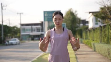 Güzel Asyalı kadın spor yapıyor, doğa parkında egzersiz yapmadan önce ya da sonra esniyor, yaşam tarzı, spor, sağlık için uygunluk.