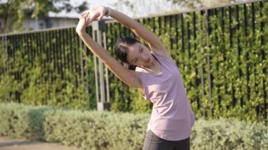 Güzel Asyalı kadın spor yapıyor, doğa parkında egzersiz yapmadan önce ya da sonra esniyor, yaşam tarzı, spor, sağlık için uygunluk.