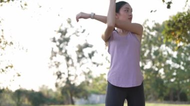 Güzel Asyalı kadın spor yapıyor, doğa parkında egzersiz yapmadan önce ya da sonra esniyor, yaşam tarzı, spor, sağlık için uygunluk.
