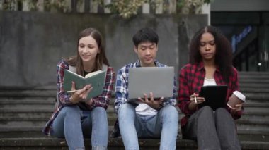 Birkaç nesil boyunca parlak genç öğrenciler parkta sınavlar için hazırlanıyorlar. Birlikte kitap okuyun ve dizüstü bilgisayar eğitimi kavramını kullanın. Akıllı öğrenci öğretmeniyle açık havada mutlu bir ders alıyor..