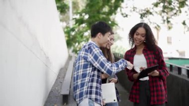 Birkaç nesil boyunca parlak genç öğrenciler parkta sınavlar için hazırlanıyorlar. Birlikte kitap okuyun ve dizüstü bilgisayar eğitimi kavramını kullanın. Akıllı öğrenci öğretmeniyle açık havada mutlu bir ders alıyor..